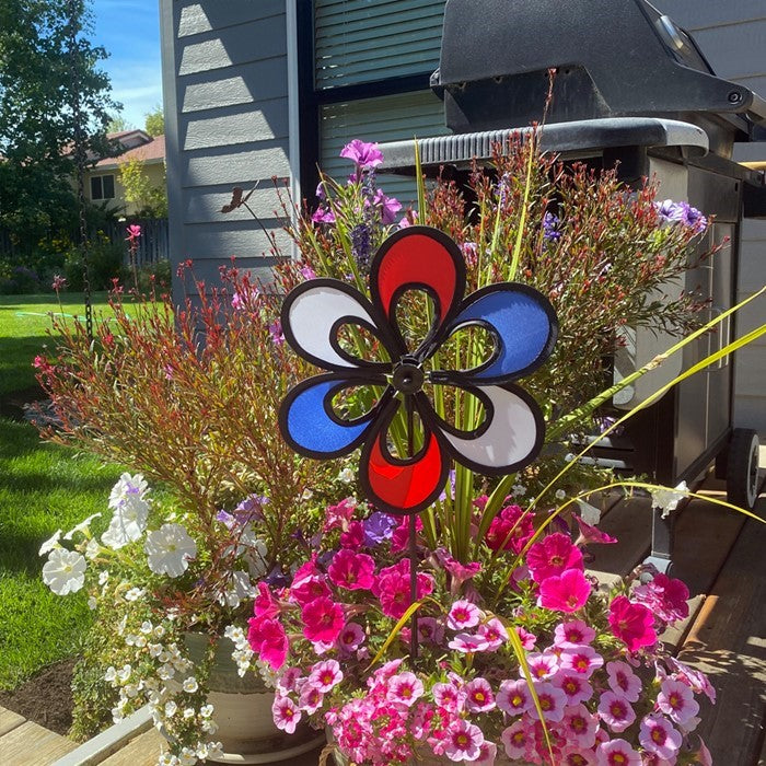 10-inch Red, White and Blue Windee Wheelz Spinner spinning in the garden, featuring an open-center petal design with vibrant colors.