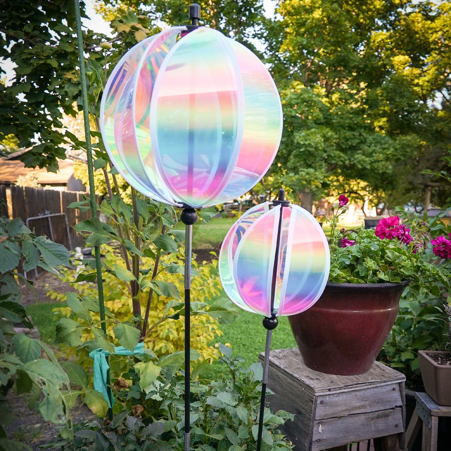 An 11" striped iridescent gazing ball displayed in a garden, featuring colorful reflections and a durable pole for stability.