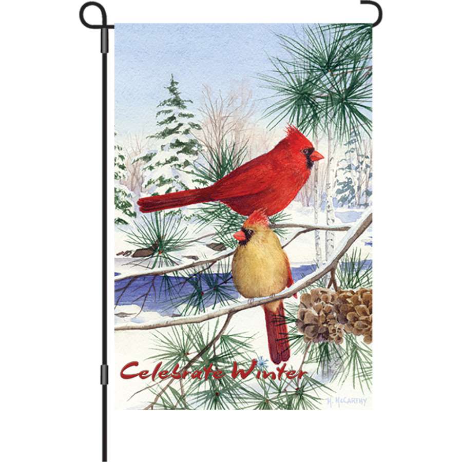12 in. garden flag featuring Cedar Farm Cardinals design on a winter backdrop, displayed outdoors in a garden setting.
