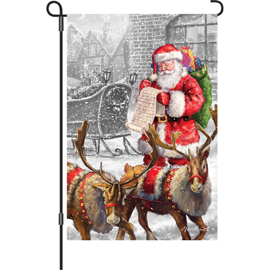 12 in. Check It Twice illuminated garden flag featuring a colorful winter design displayed outdoors, radiating festive cheer at night.