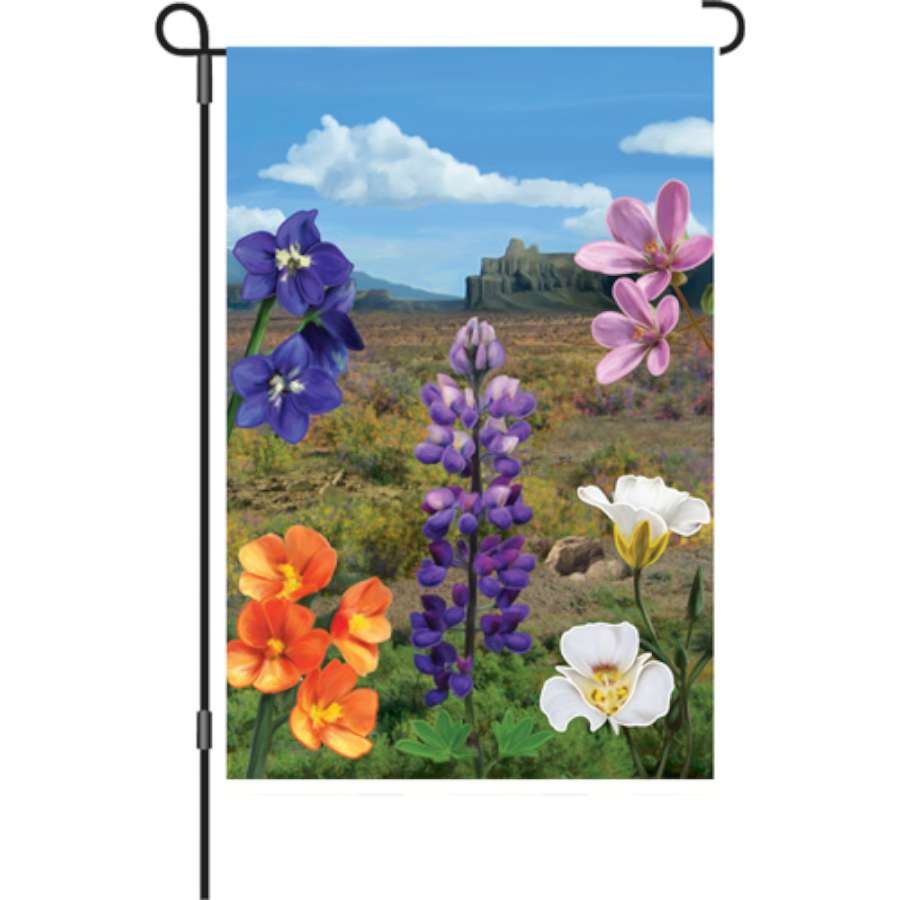 12 in. Desert In Bloom garden flag with vibrant floral designs displayed in a flower bed, showcasing outdoor decor charm.