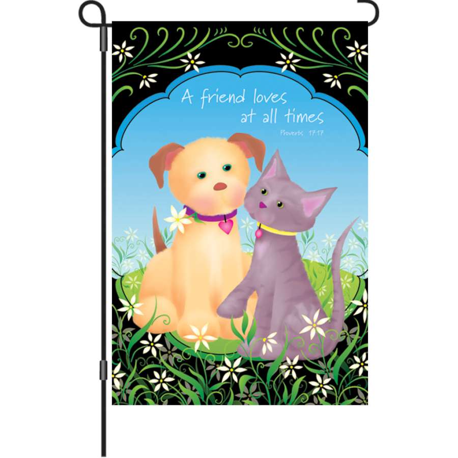 12 in. Flag depicting 'A Friend Loves at All Times' in colorful letters, displayed in a garden setting among flowers and greenery.