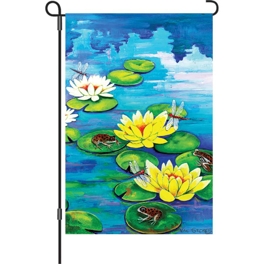 12 in. garden flag featuring cheerful Frisky Frogs design, displaying bright colors on a decorative stand in a garden setting.