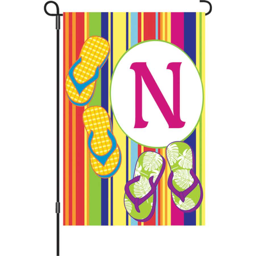 12 in. Summer Monogram Flag - N featuring a vibrant letter N design proudly displayed in a garden setting.