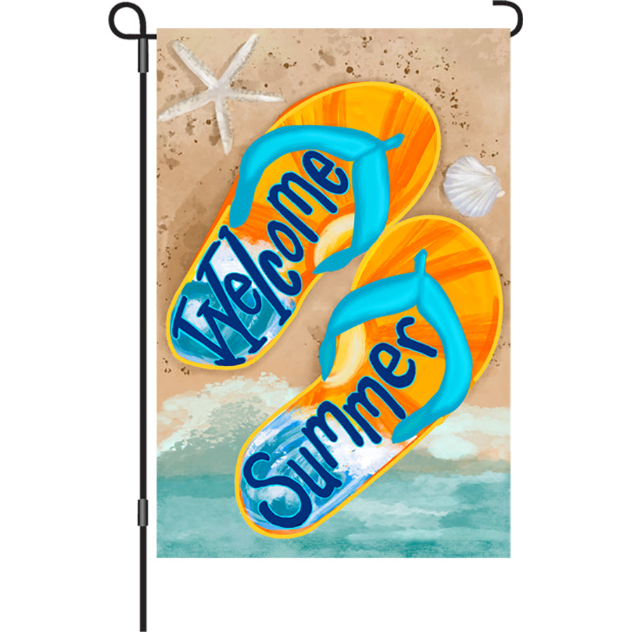 12 in. Summer Welcome garden flag featuring colorful flip-flops on sand, displayed outdoors with the breeze making it flutter.
