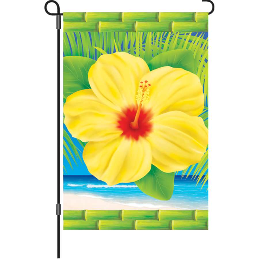 12 In Tropical Hibiscus garden flag featuring vibrant floral design, displayed on a flag stand in a sunny outdoor garden setting.