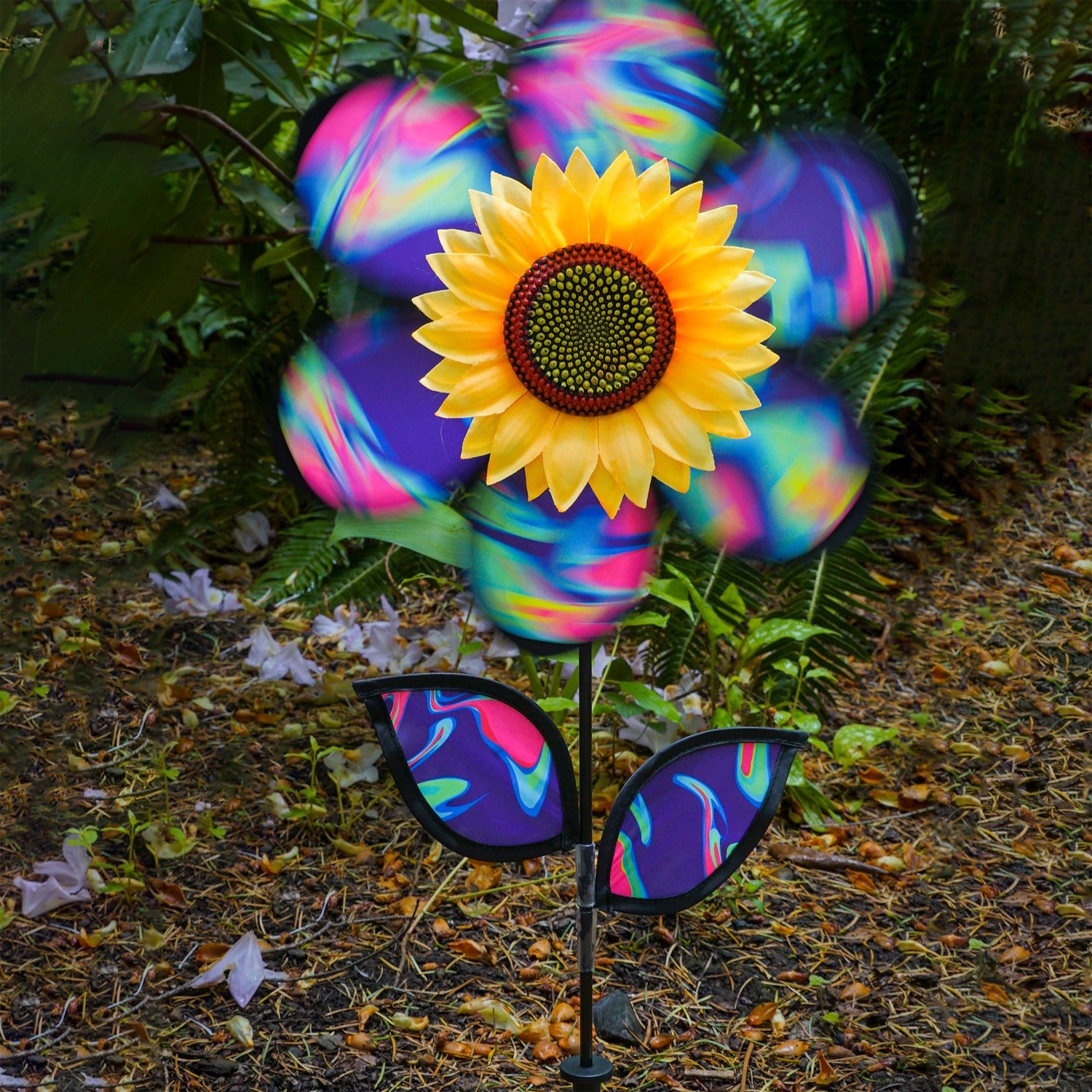 12\" Blue Psychedelic Sunflower garden spinner with colorful petals in motion, surrounded by greenery, enhancing outdoor aesthetics.