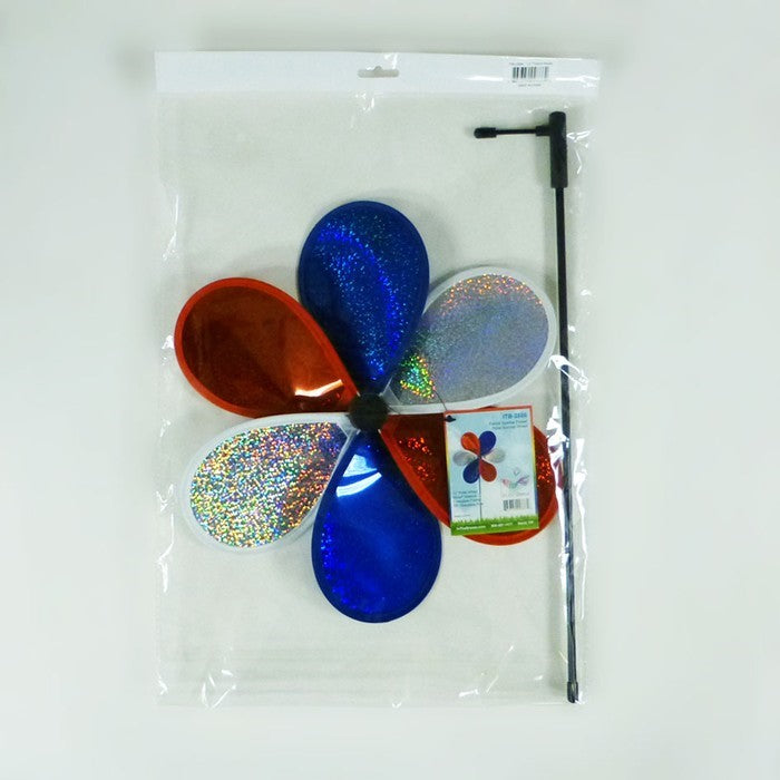 12-inch Patriot Sparkle Flower with red, white, and blue Mylar petals spinning on a fiberglass pole in a sunny garden setting.
