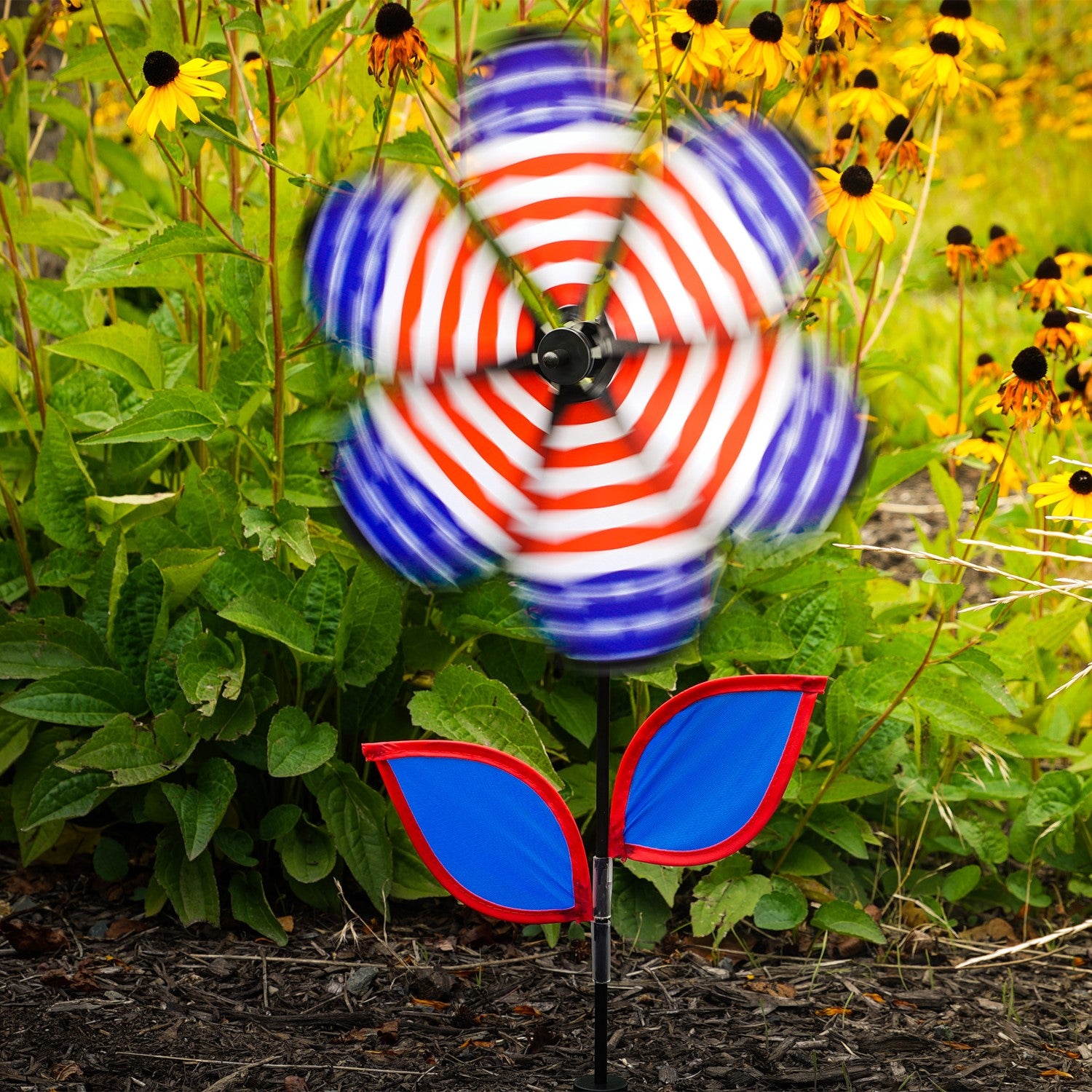 12-inch Patriotic Flower Spinner with stars and stripes petals, colorful leaves on a fiberglass stem, elegantly spinning in the breeze.