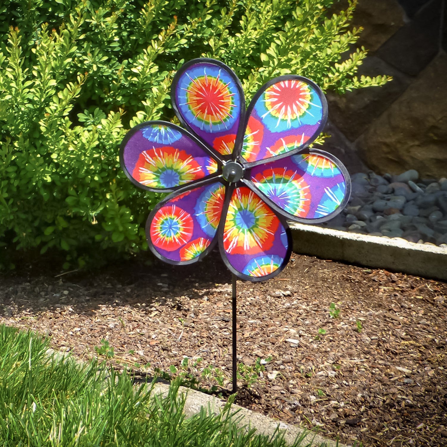 12-inch Tie Dye Flower garden spinner with colorful petals spinning in the breeze on a fiberglass pole, enhancing garden decor's vibrancy.