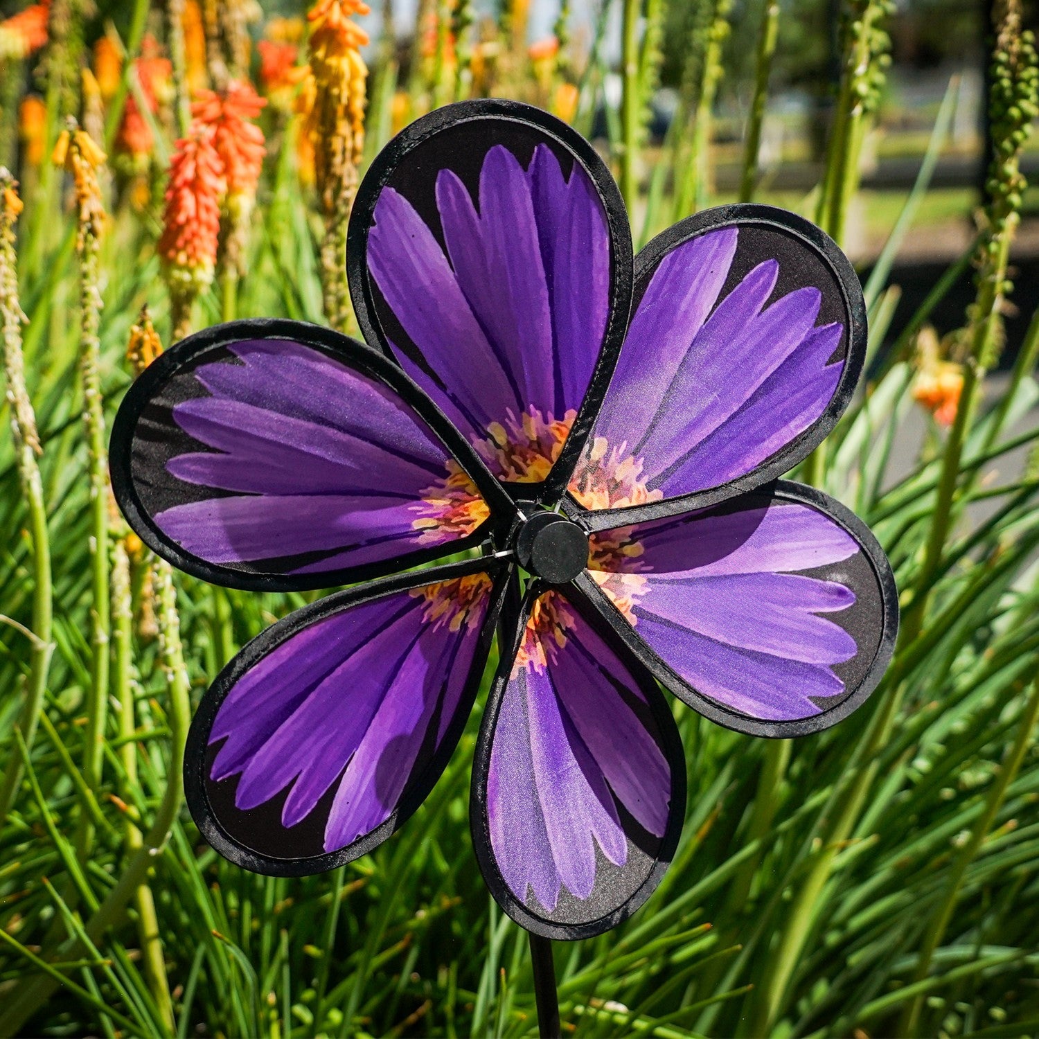 13.5-inch Aster Spinner with vibrant petals and green leaves, showcasing realistic flower design in an outdoor garden setting.