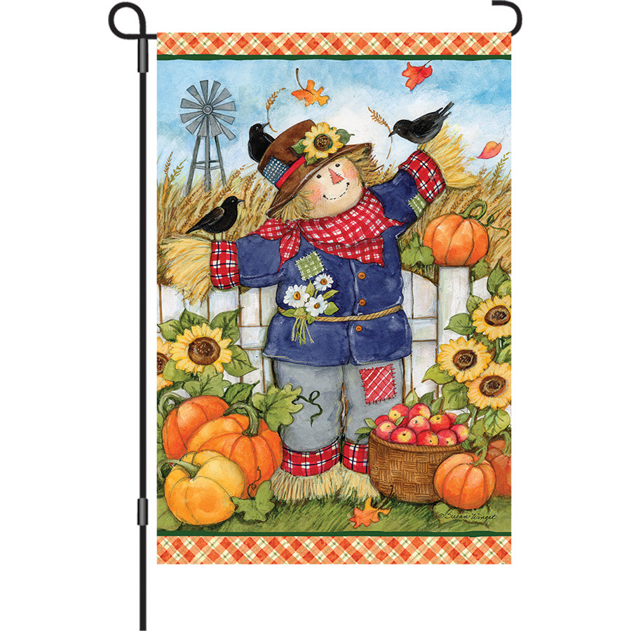 13 in. Elite Oversized Garden Flag with a plaid scarecrow design displayed on a flag pole in an autumn garden setting.