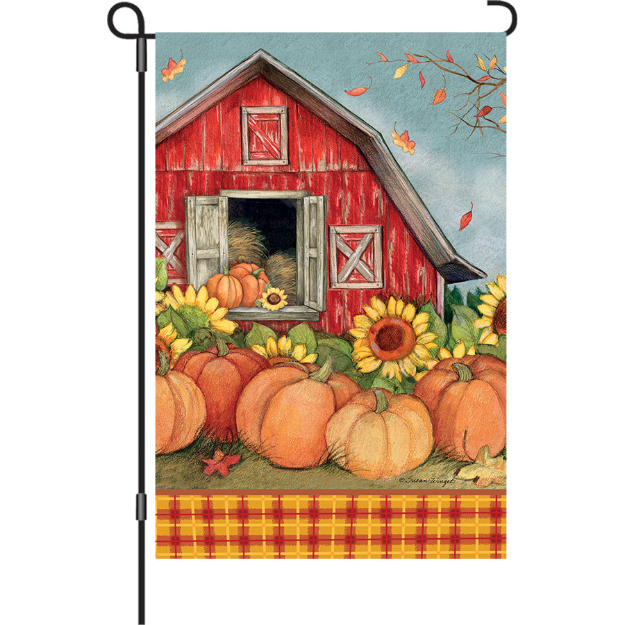 13 in. Elite Oversized Garden Flag featuring a vibrant pumpkin barn design, showcasing rich autumn colors in a garden setting.