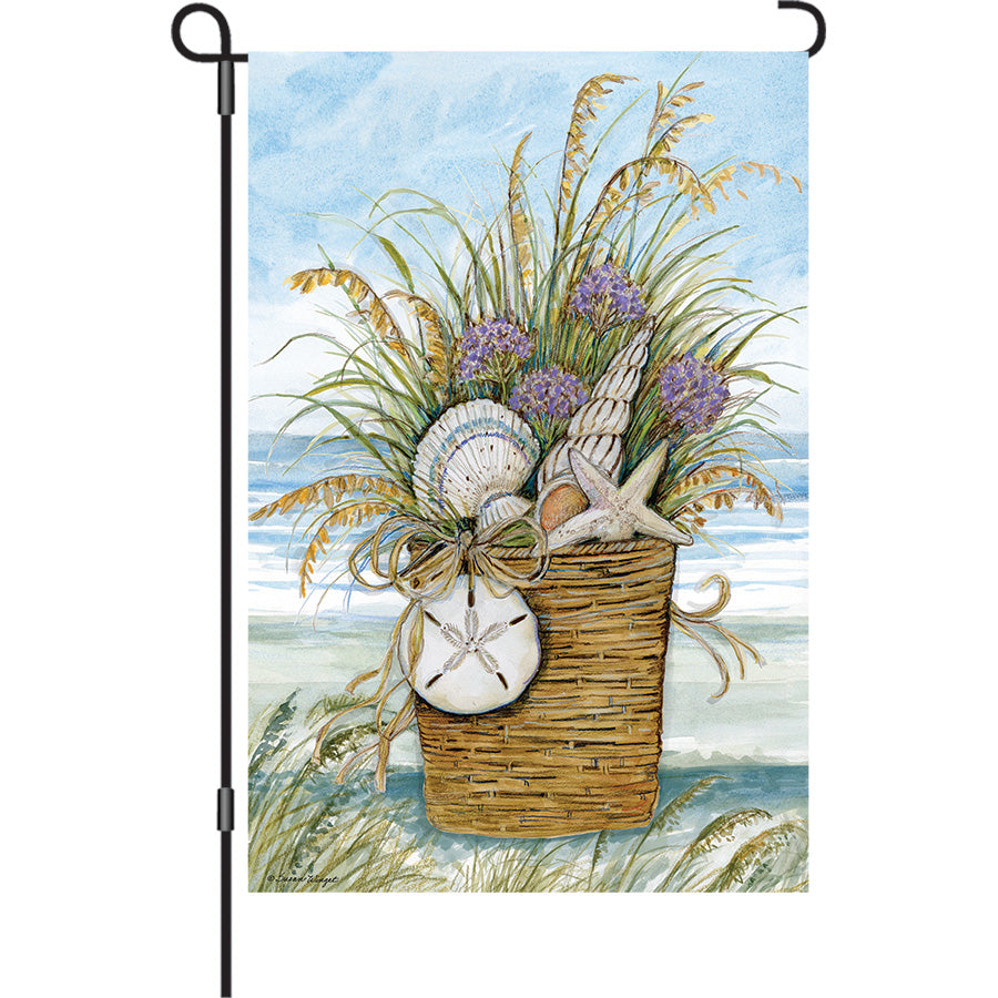 13 in. Elite Oversized Garden Flag with a colorful shell basket design, gently waving on a standard garden flagpole amidst a lively garden.