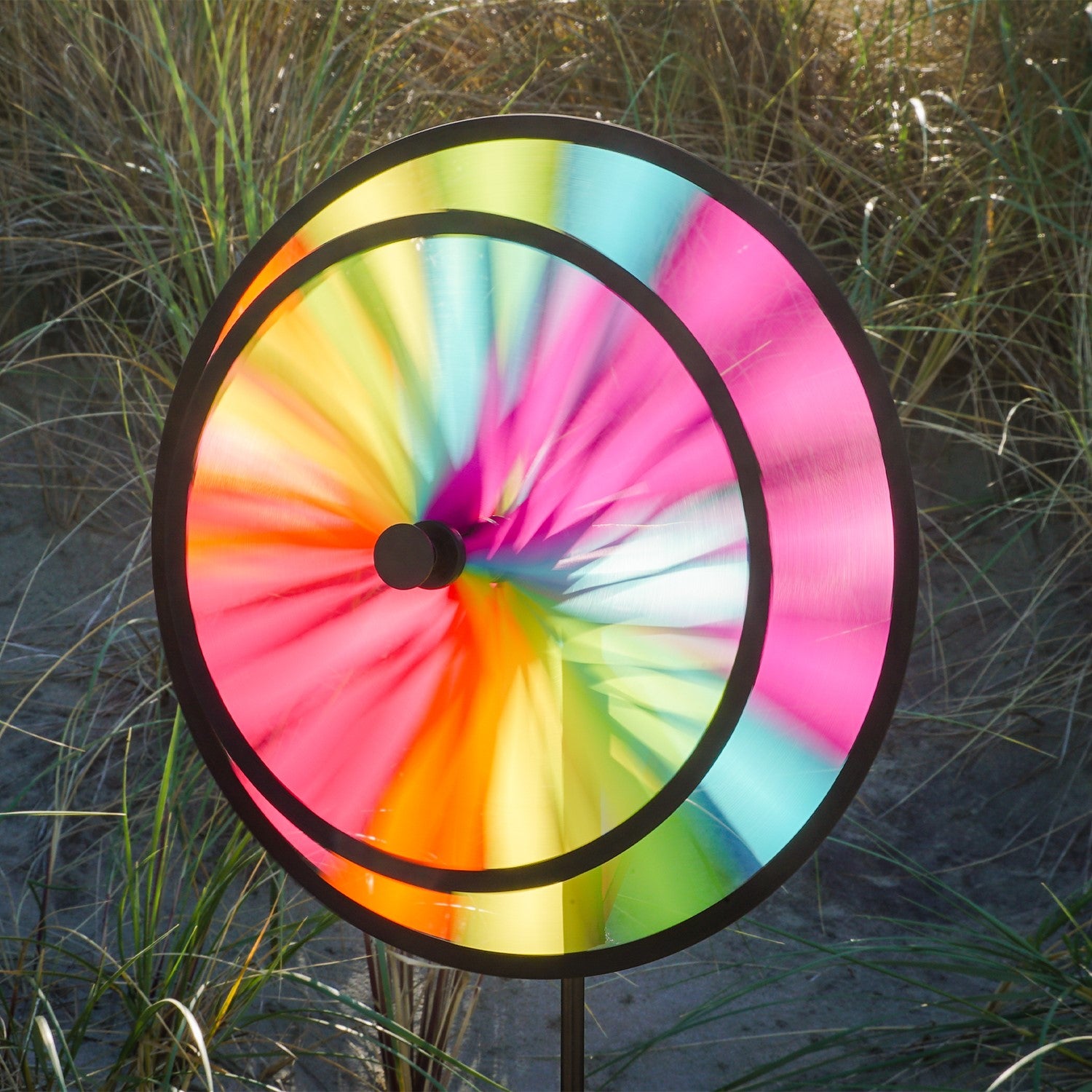13-inch Fiesta Double Spinner with Wind Sail showcasing vibrant colors and dual spinning wheels, placed in a garden setting.