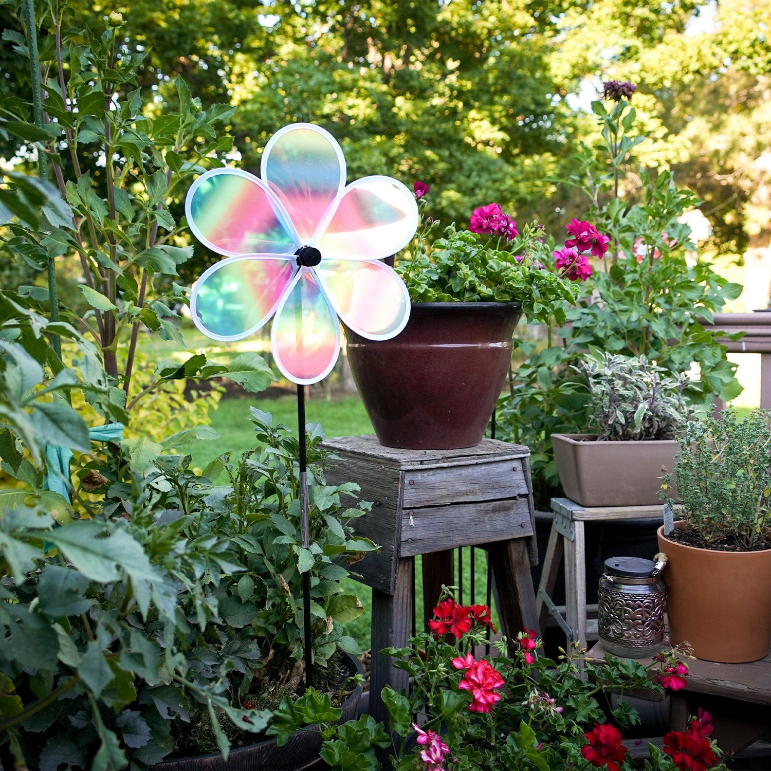 13.5-inch striped iridescent flower spinner with colorful stripes and a shimmering finish, spinning in a garden setting.