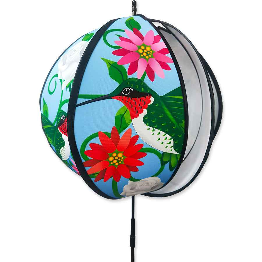 15 in. Ball Spinner featuring colorful hummingbirds and flowers, 15 inches in diameter, elegantly rotating on a ground stake in a garden setting.