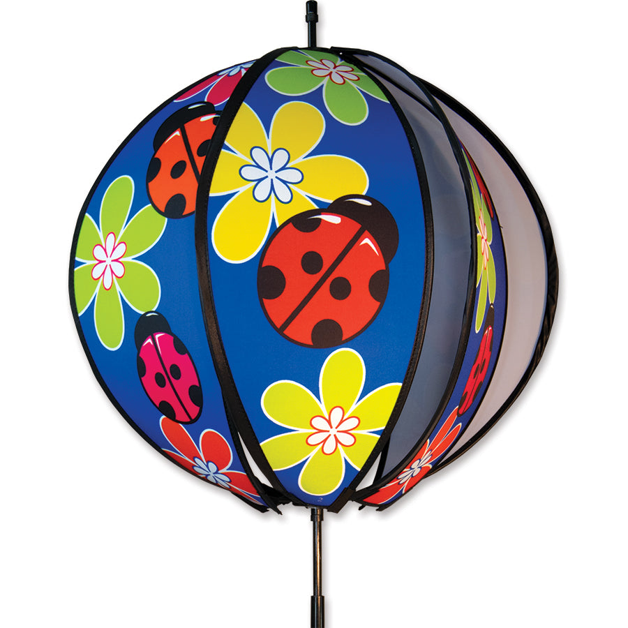 15 in. Ball Spinner featuring vivid ladybug designs on six colorful panels, spinning on a garden stake in a sunny outdoor setting.