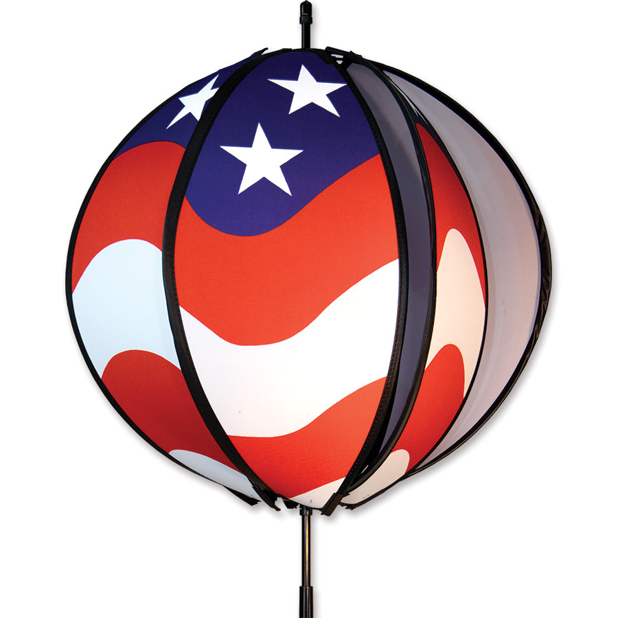 15 in. Ball Spinner featuring six colorful panels of the American flag spinning outdoors on a ground stake in a garden setting.