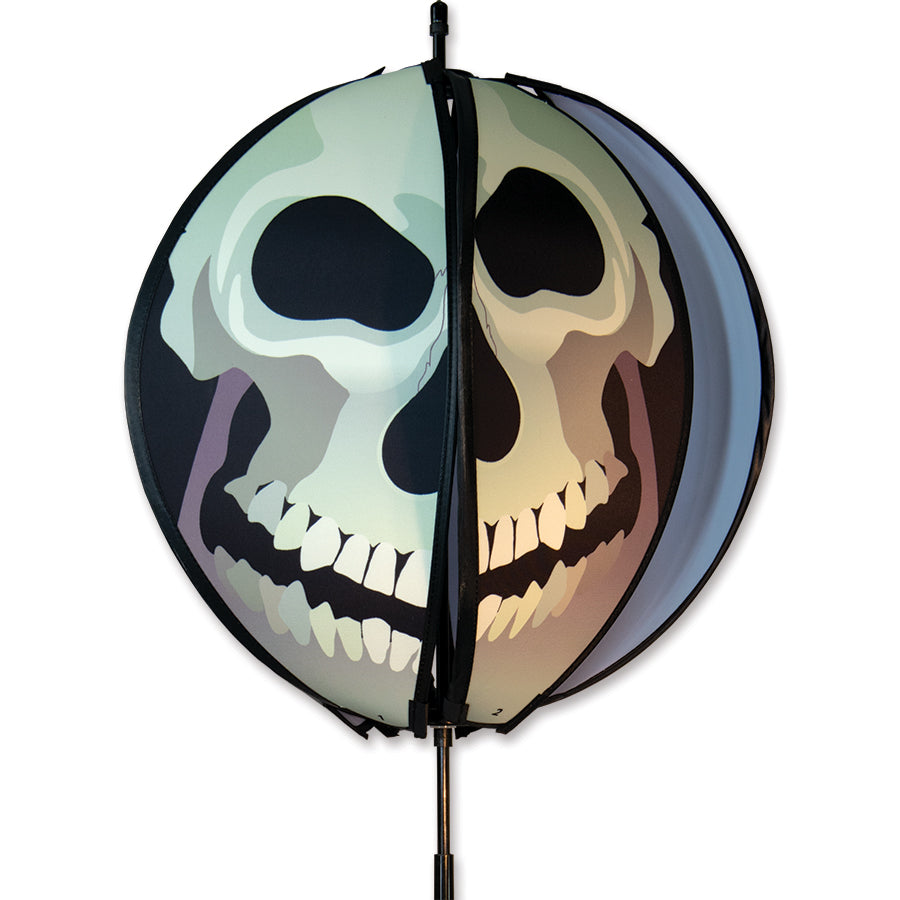 15 in. Ball Spinner featuring a vibrant skull design with six colorful panels spinning gracefully in a garden setting.