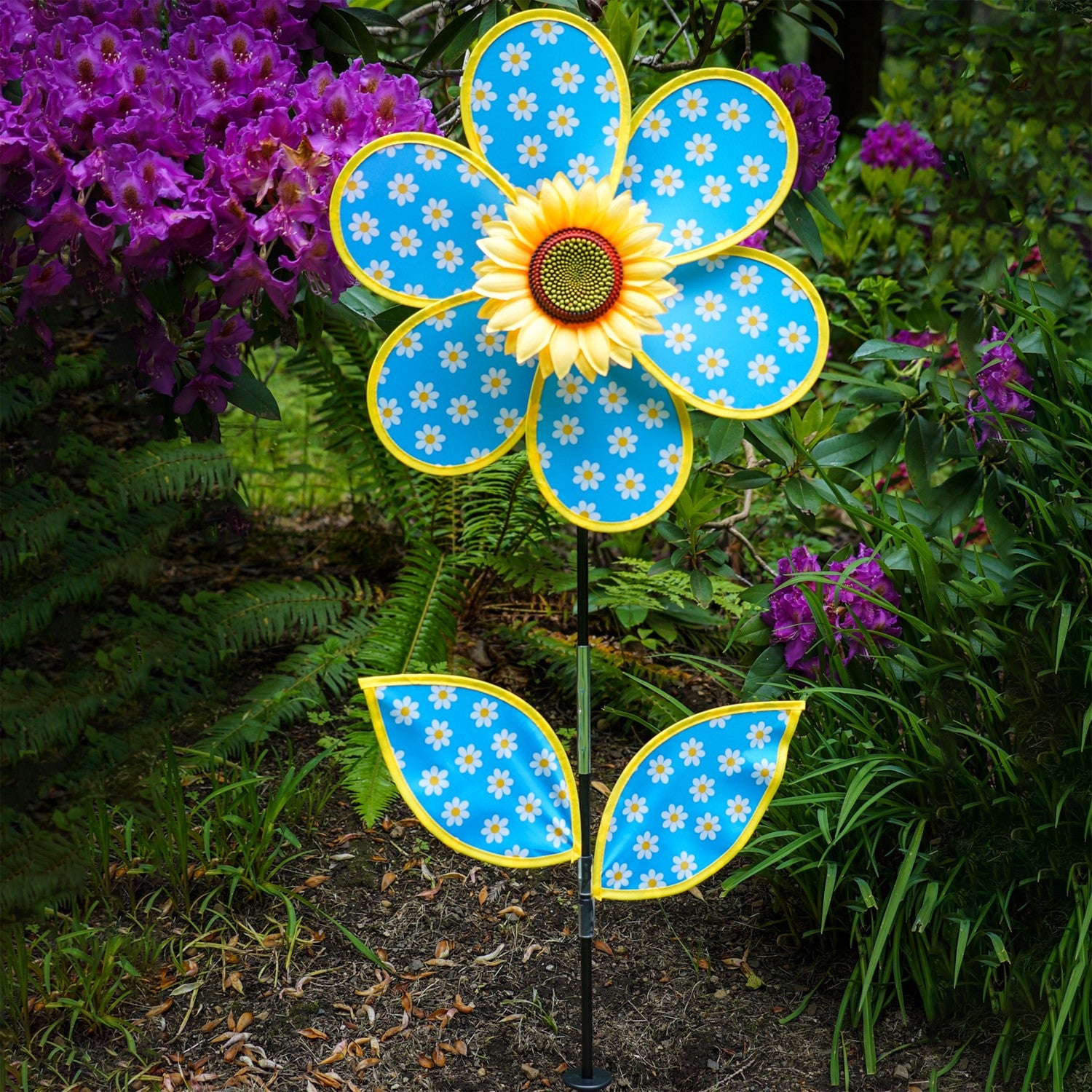 Colorful 16-inch Daisy Sunflower with Leaves spinner featuring polka dot petals and a realistic sunflower center, displayed outdoors in a garden setting.