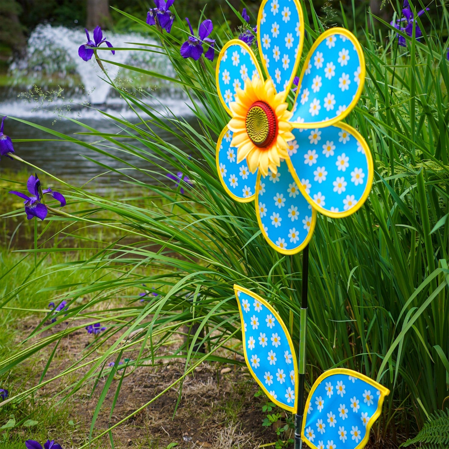 Colorful 16-inch Daisy Sunflower with Leaves spinner featuring polka dot petals and a realistic sunflower center, displayed outdoors in a garden setting.