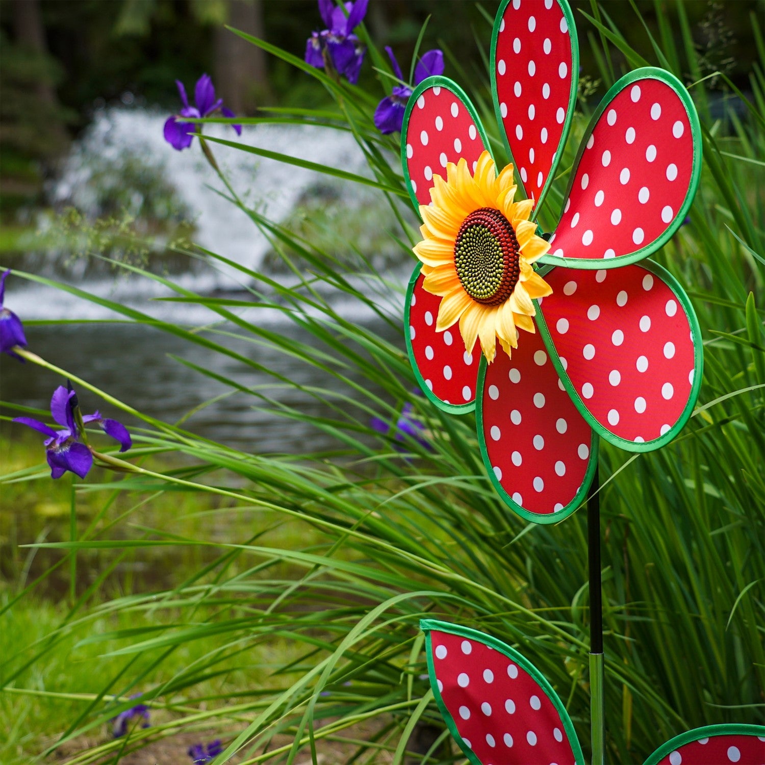 16" Polka Dot Flower with Leaves garden spinner featuring red and white polka dot petals and a sunflower center, displayed outdoors.
