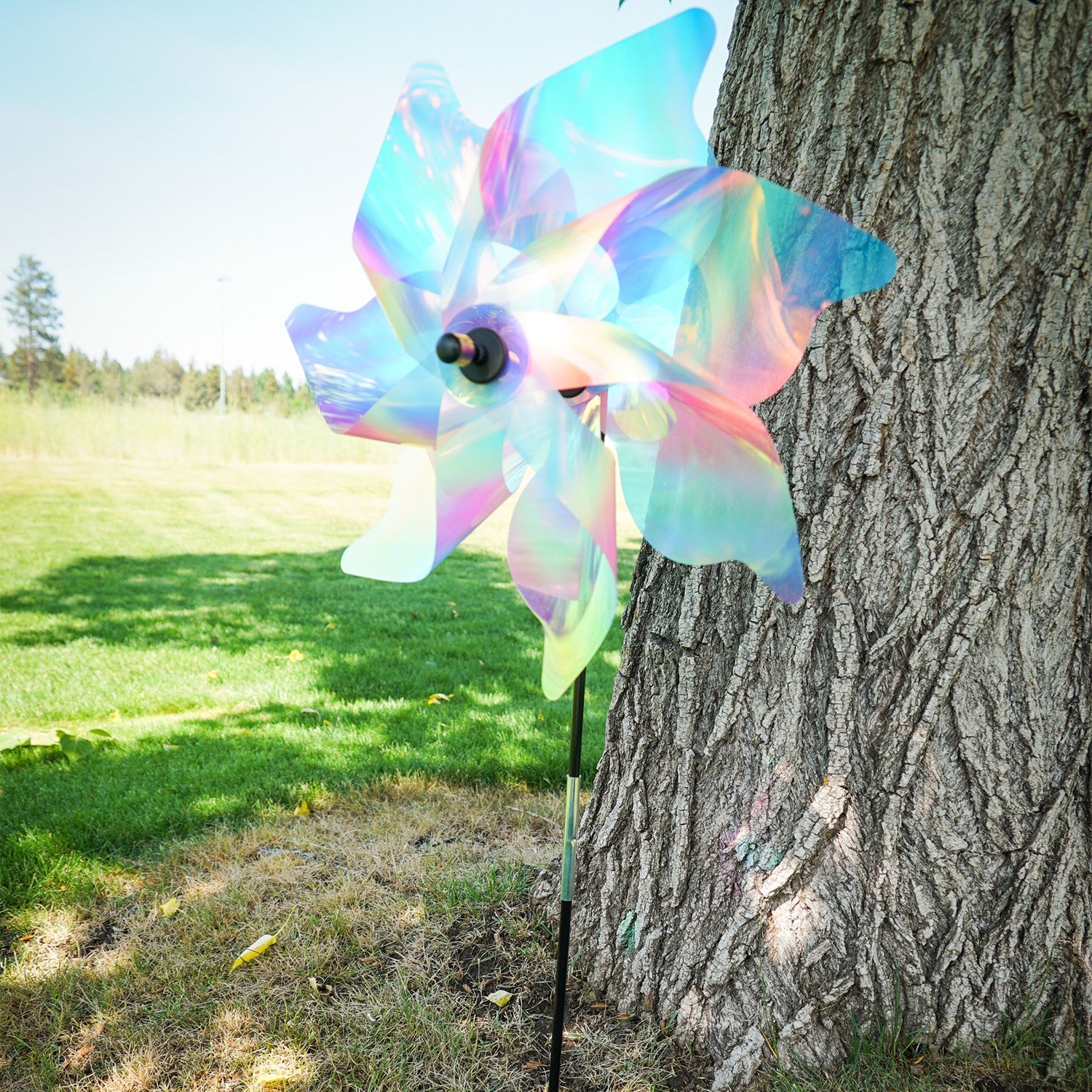 18-inch striped iridescent pinwheel spinner made of durable Mylar, vibrant pastel colors, displayed outdoors in a garden setting.
