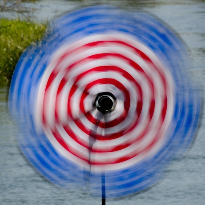 19-inch Patriotic Flower with Leaves spinning outdoors, showcasing bright stars and stripes petals attached to a sturdy fiberglass pole.