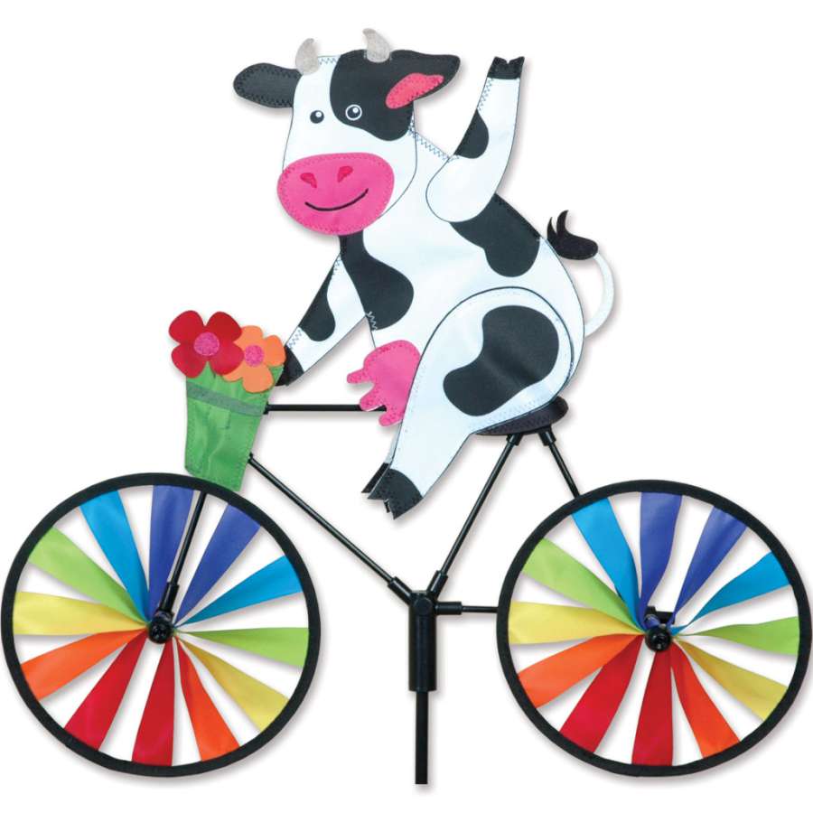 20 in. Bike Spinner - Cow featuring a vibrant cow design, gracefully spinning in the breeze in an outdoor garden setting.