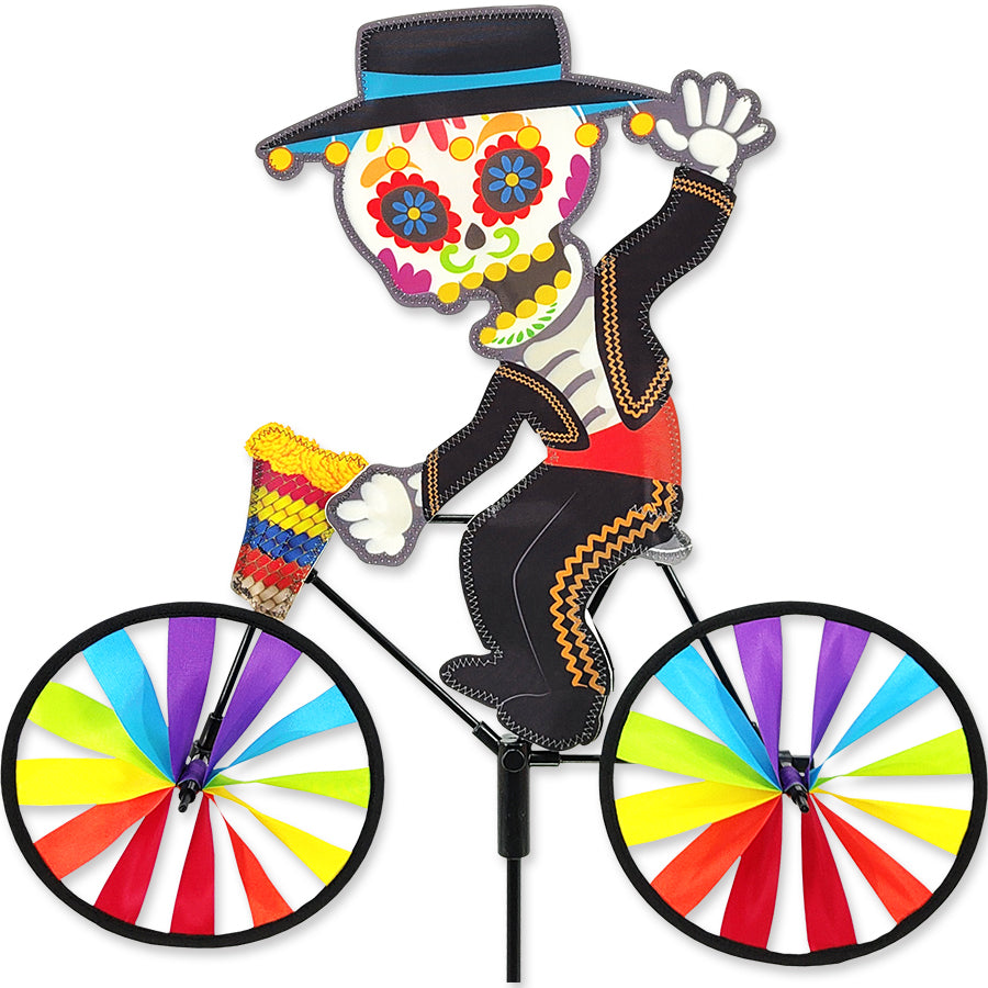 20 in. Bike Spinner - Day of the Dead featuring vibrant fabric patterns spinning against a backdrop of greenery in an outdoor setting.