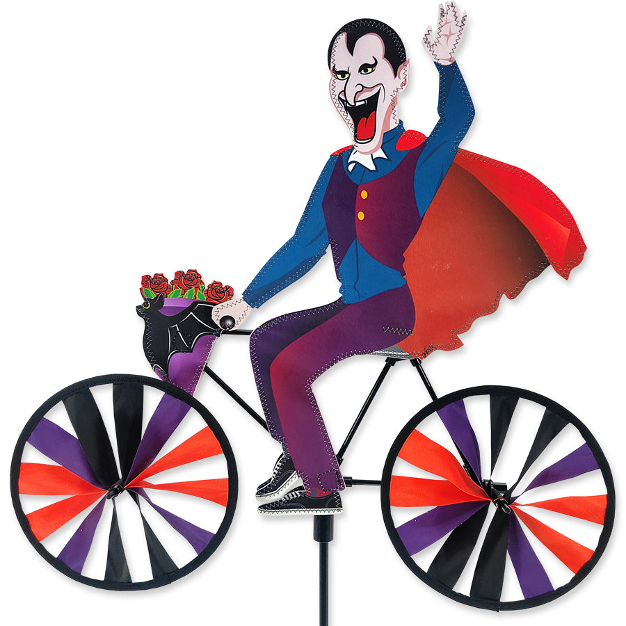 20 in. Bike Spinner featuring a colorful Dracula design, spinning in a garden outdoors, showcasing vibrant colors against greenery.