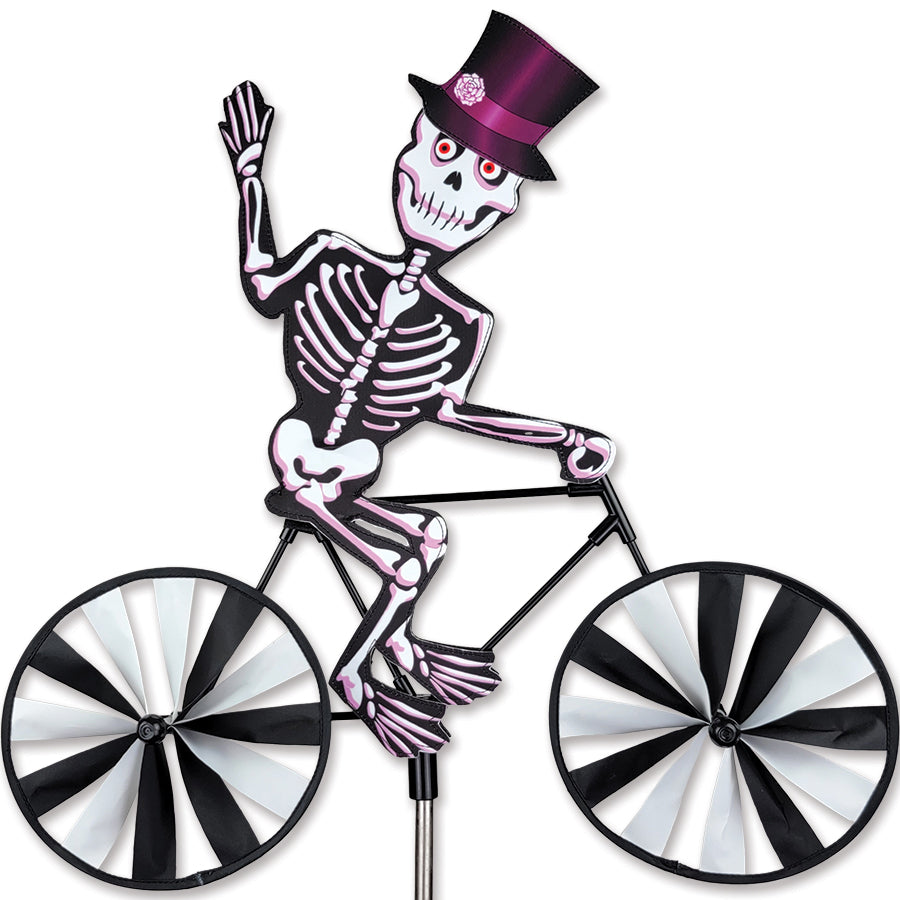 20 in. Bike Spinner - Skeleton featuring colorful skeleton design spinning gently in a garden setting, creating lively outdoor decor.