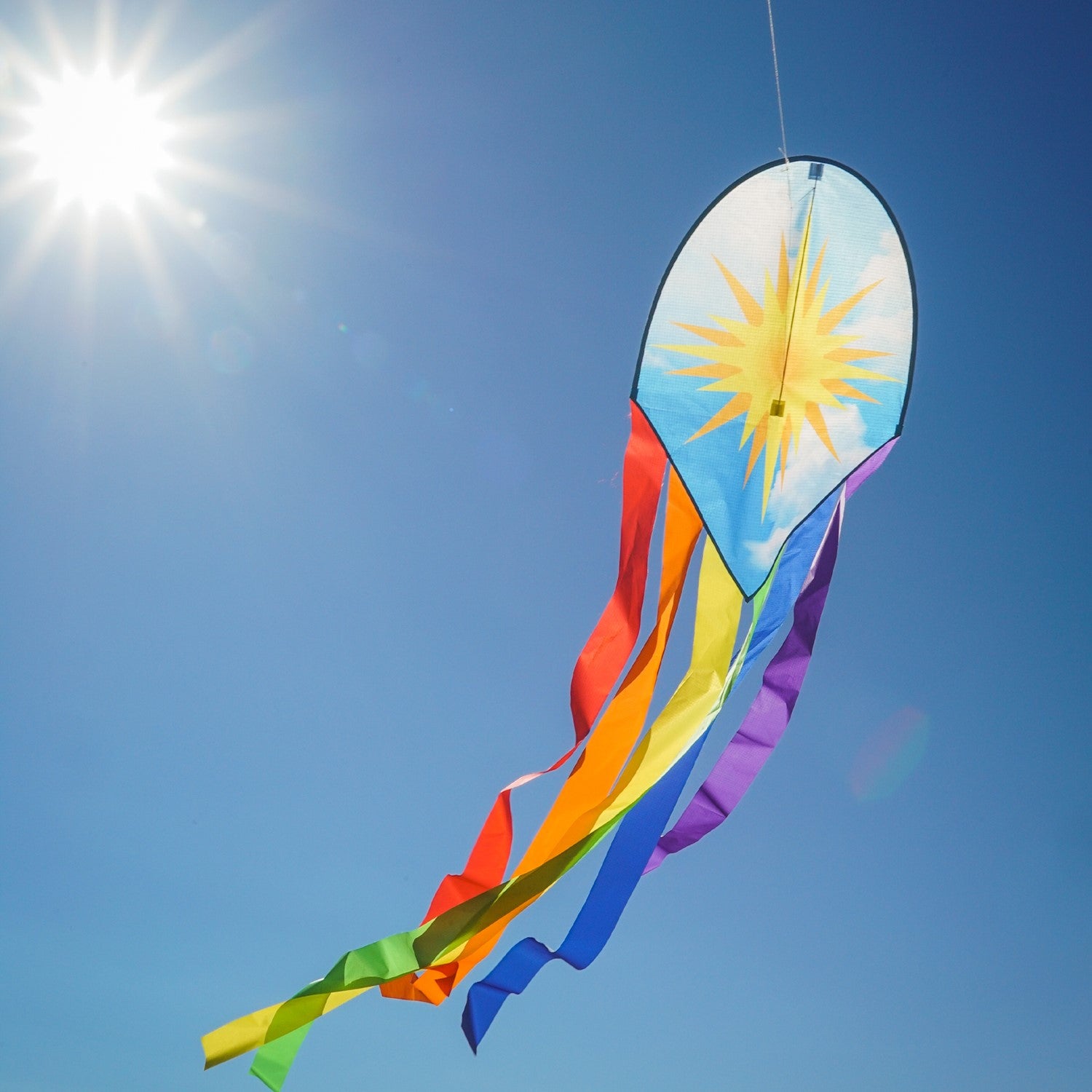 22-inch Sun & Rainbow Dancing Dragon Kite with colorful tails flying against a clear blue sky during a sunny day.