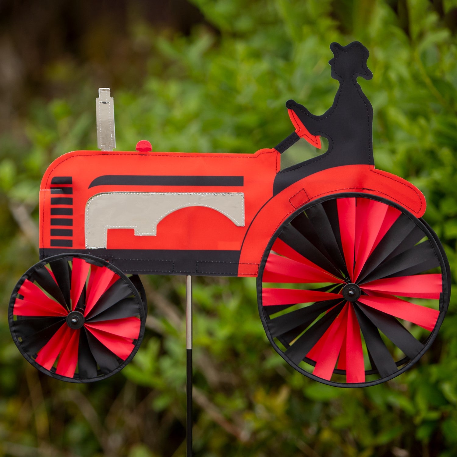 24-inch Red Tractor Spinner with four vibrant spinning wheels and applique details, delightfully showcased in an outdoor garden setting.