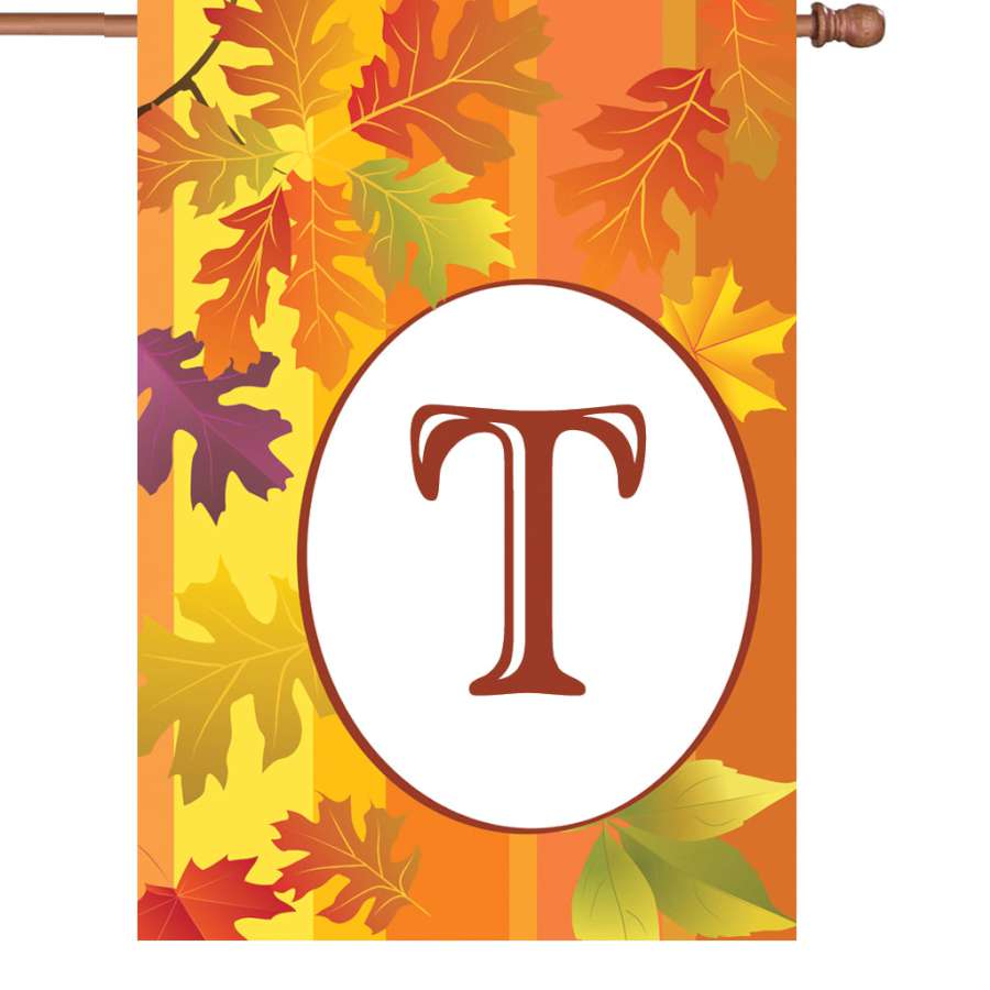 28 in. Fall Monogram Flag featuring a 'T' with autumn leaves displayed in a garden setting, showcasing vibrant fall colors.