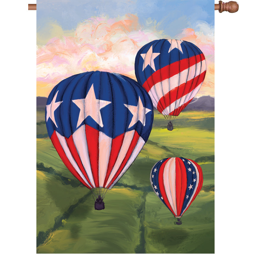 28 in. Patriotic Hot Air Balloons flag with vibrant colors displayed on a garden pole in an outdoor setting, illuminating the yard.