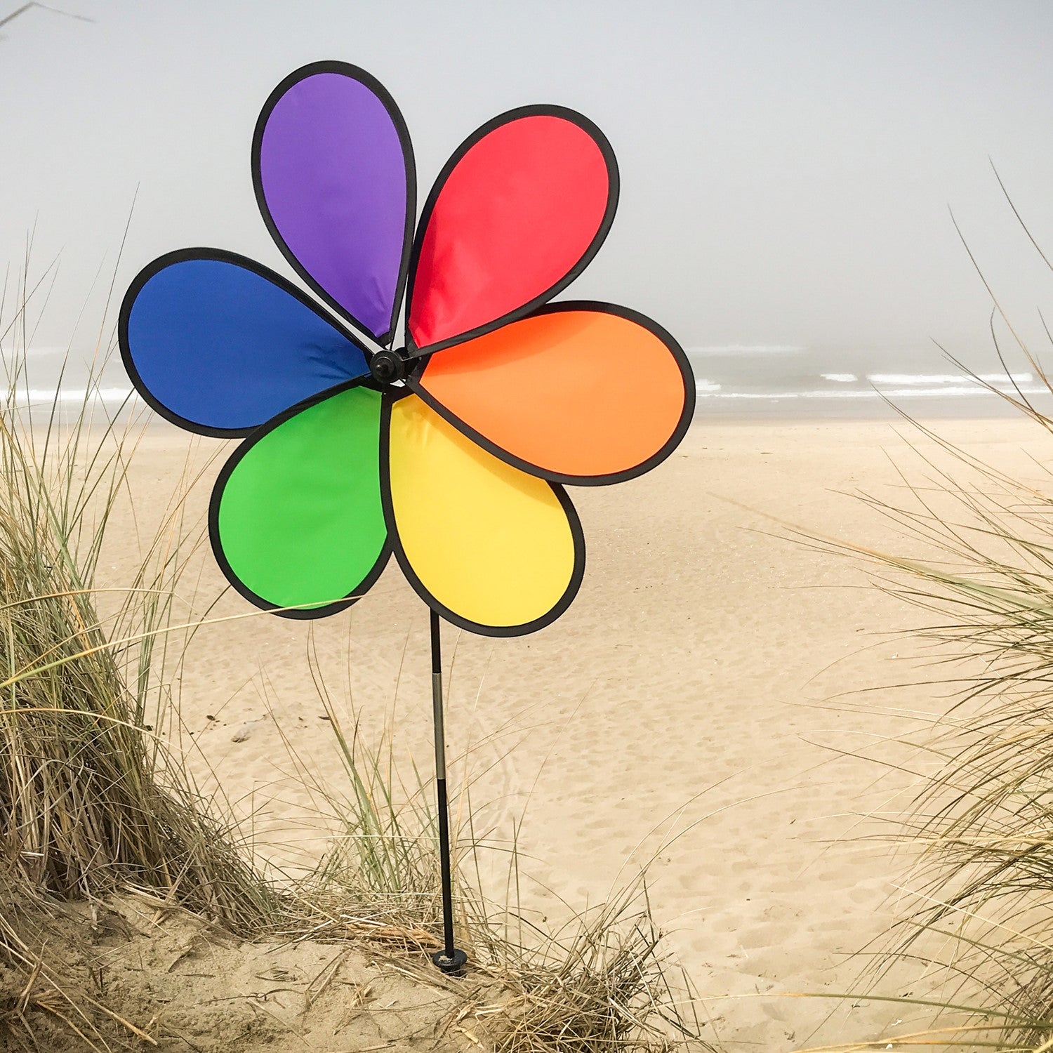Large 30-inch 6-Petal Rainbow Flower spinner in vibrant colors displayed in a garden setting, spinning gently in the breeze.