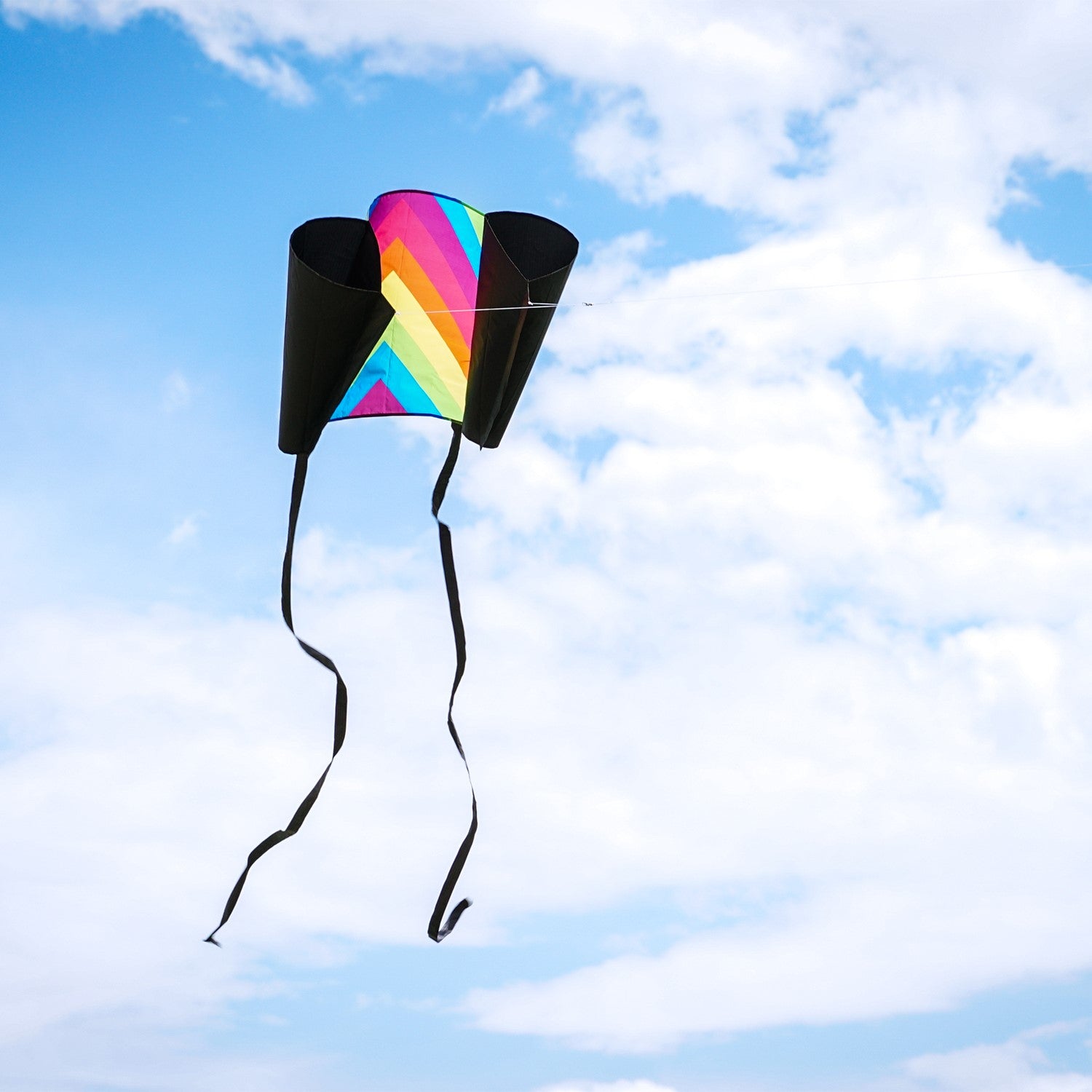 30-inch Neon Fiesta Stripe Sled Kite in vibrant colors flying high with black tails, suitable for beginners and easy to pack.
