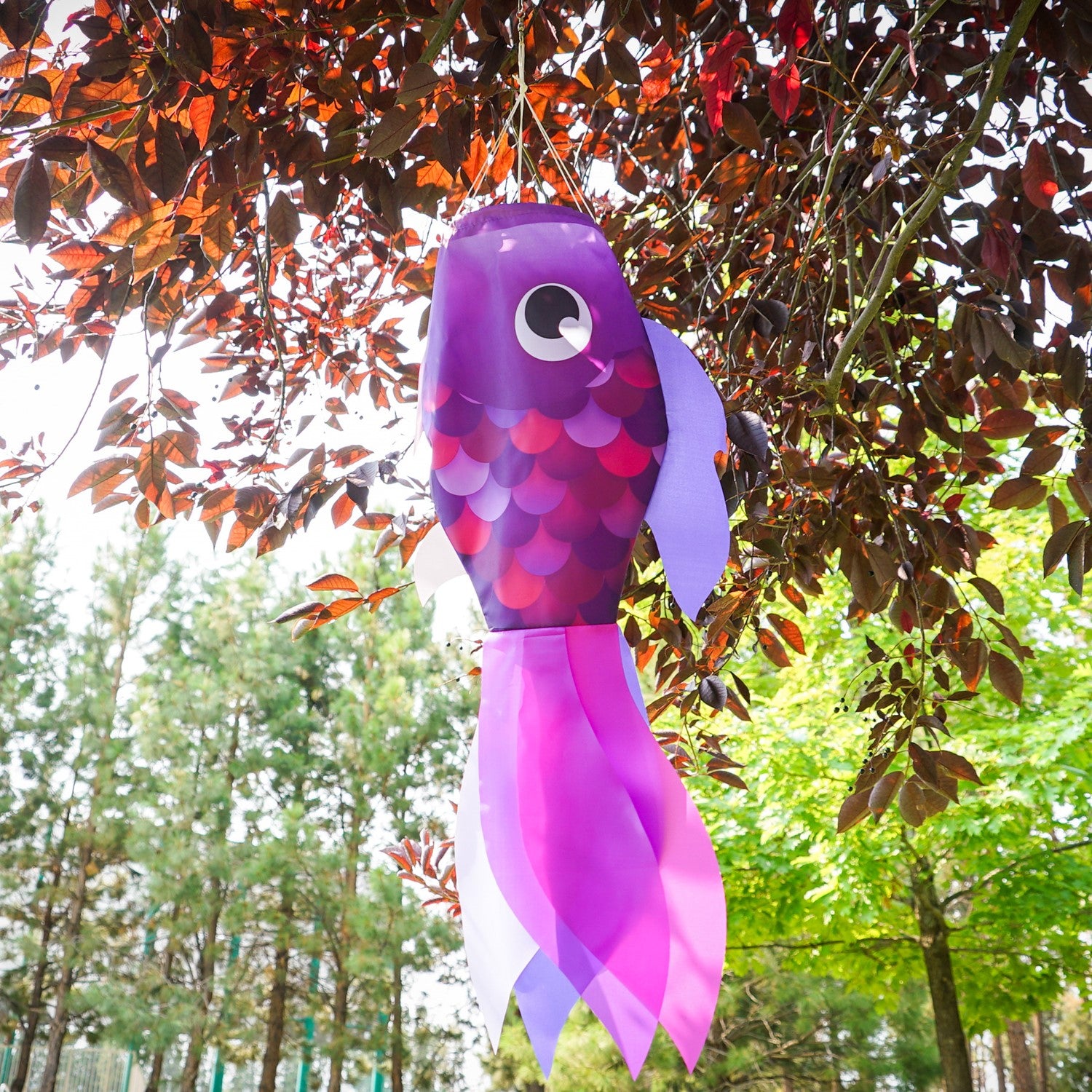 30" Lavender Damsel Fish wind sock with vibrant lavender coloration and free-flowing fins displayed outdoors in a garden setting.