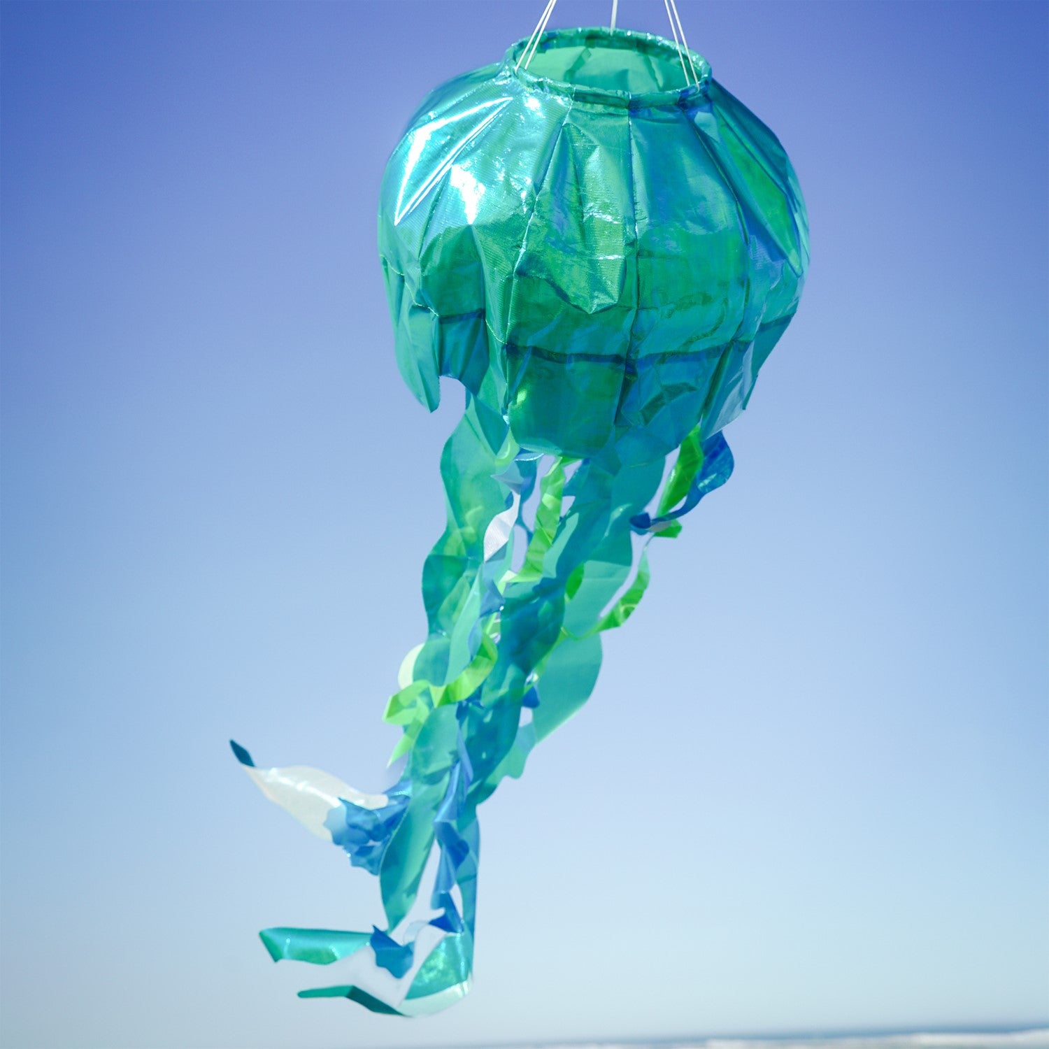 A beautiful 40" Teal Iridescent Jellyfish 3D Windsock with 12 flowing tentacles, designed for outdoor display, showcasing captivating ocean-inspired decor.