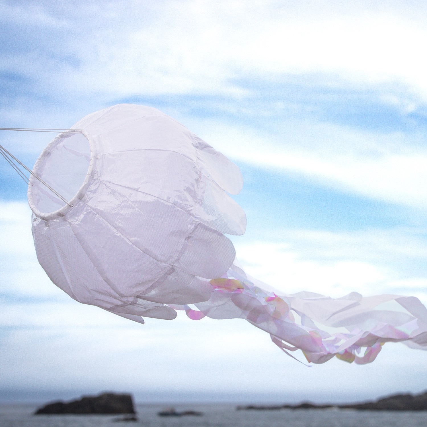 A 40-inch White Iridescent Jellyfish 3D Windsock swaying in the wind, highlighting its shimmering fabric and lifelike tentacles.
