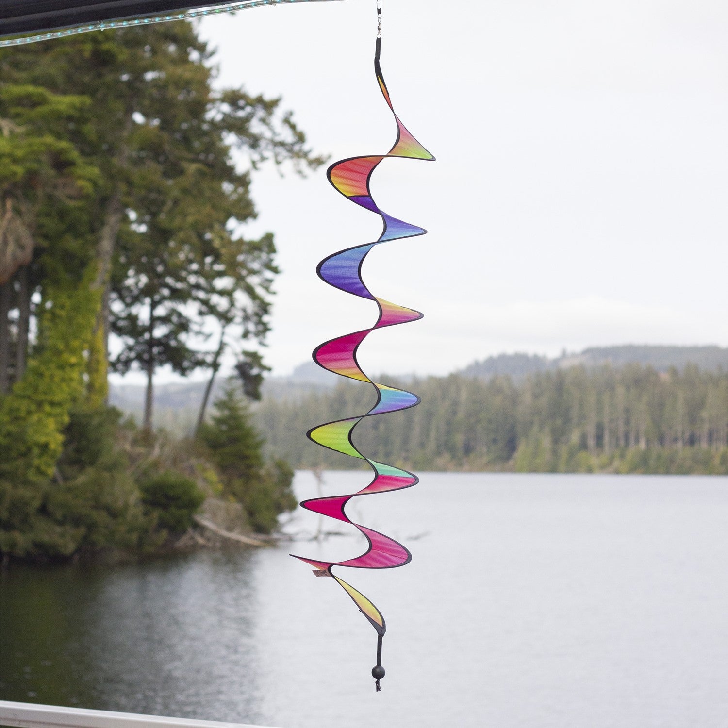 48-inch Jewel Curlie featuring a rainbow design, elegantly swirling and suspended in an outdoor garden setting.