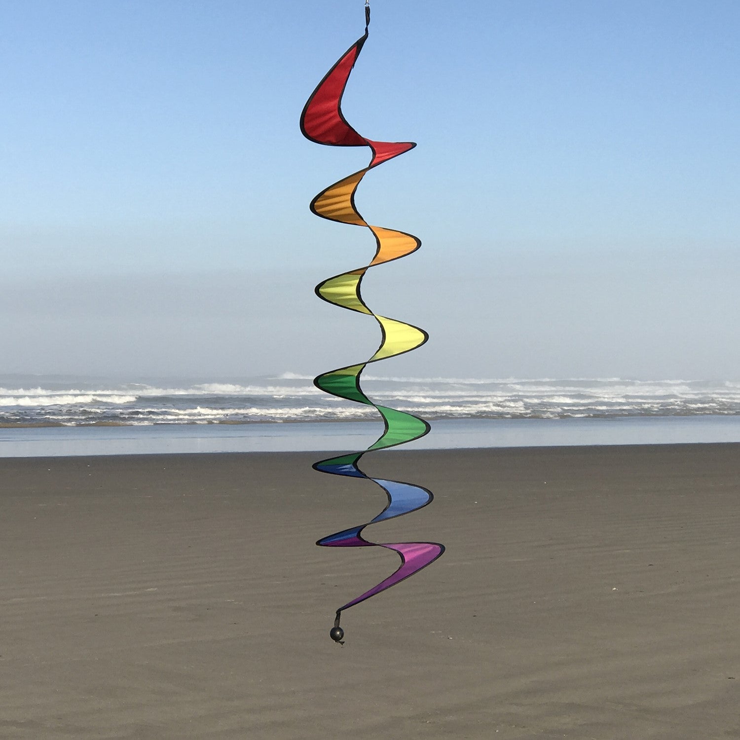 Vibrant 48-inch Rainbow Curlie fluttering in the wind, showcasing bold colors and dynamic movement against a clear sky.