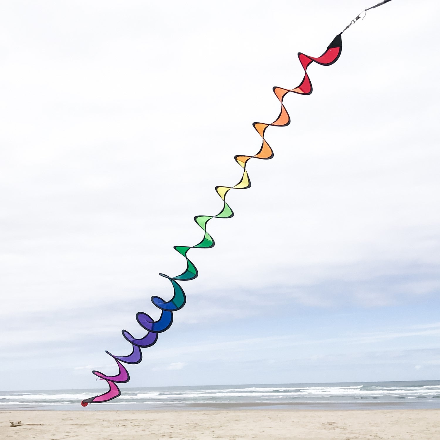 48-inch Rainbow Thin Curlie hanging in a garden, showcasing vibrant colors and a whimsical design that spins in the breeze.