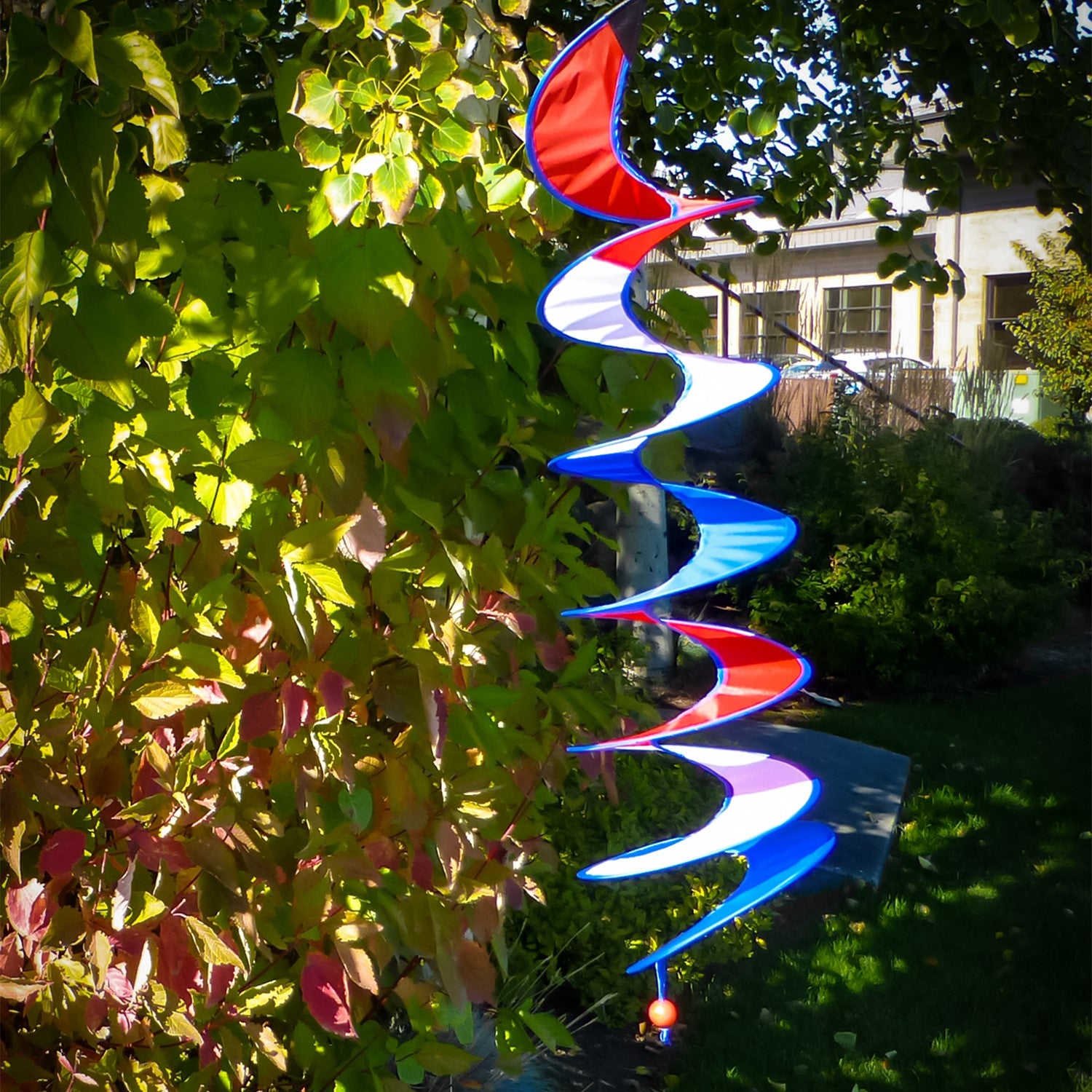 48-inch Red, White, and Blue Curlie hanging outdoors, swirling with the breeze, showcasing its vivid colors and patriotic design.