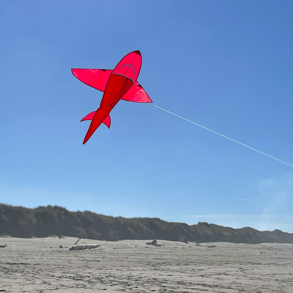 5' 3D Red Shark Kite showcasing its dynamic 3D design, with tooth-lined jaws and tail, flying gracefully against a clear blue sky.