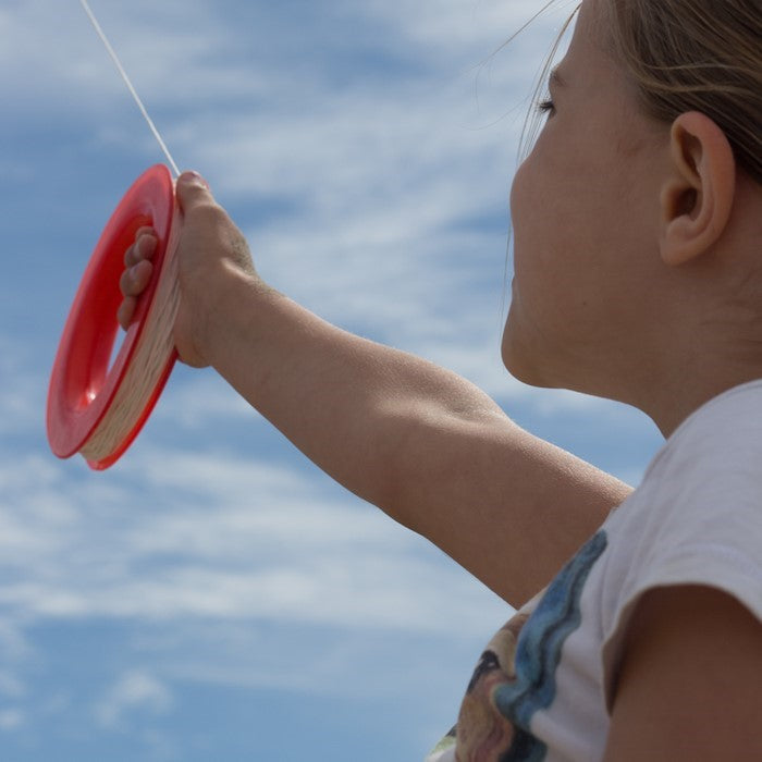 50 LB x 300' kite line on hoop featuring twisted polyester, red plastic hoop, and attached snap swivel for easy connectivity displayed outdoors.
