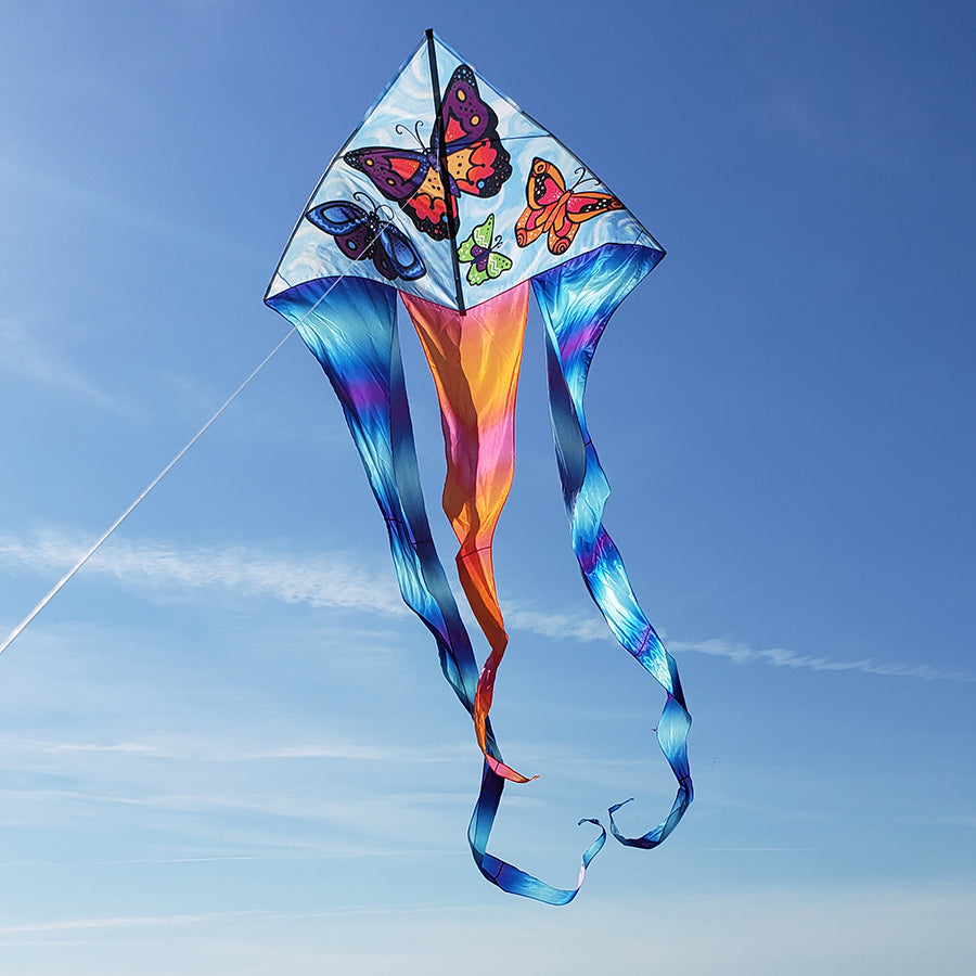 6.5 ft Flo-Tail Delta Kite featuring butterfly design soaring in the sky, displaying its flowing 24-foot tails against a blue backdrop.