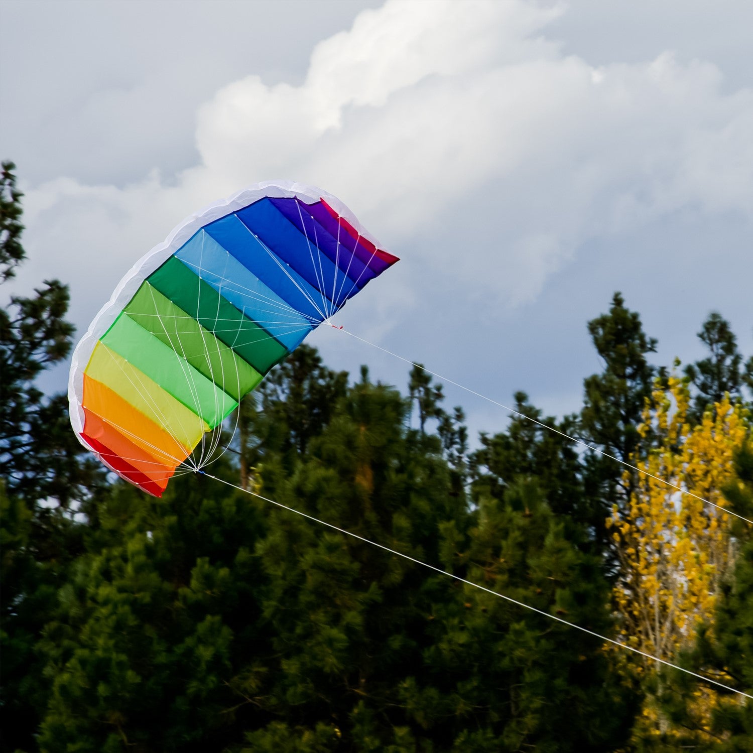 62-inch Sport Air Foil kite in rainbow colors soaring against a clear blue sky, demonstrating its aerodynamic design and double-line setup.